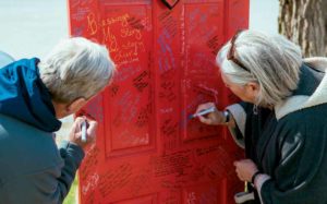Cancer survivor Alan Hecht and his wife Jackie sign one of Gilda’s Club’s signature red doors.